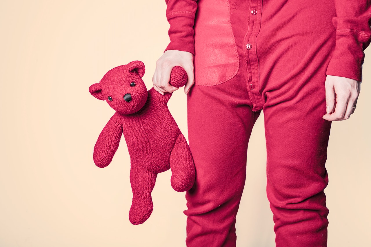 enfant en pyjama qui tient un ours en peluche